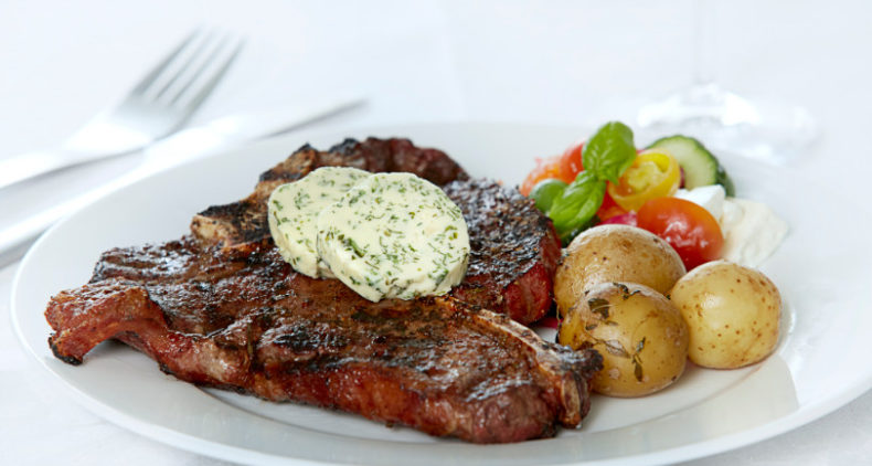 T-bone steak med grillbagte kartofler, urtesmør og græsk salat